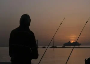 Een man die een visreis maakt naar Denemarken en geniet van de zon's ondergang.