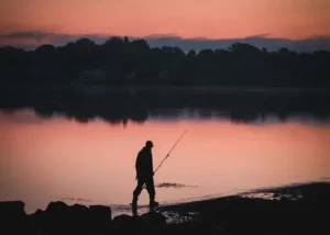 Een man die aan het duurzaam vissen is in Noorwegen. Met een geweldige zon's ondergang.